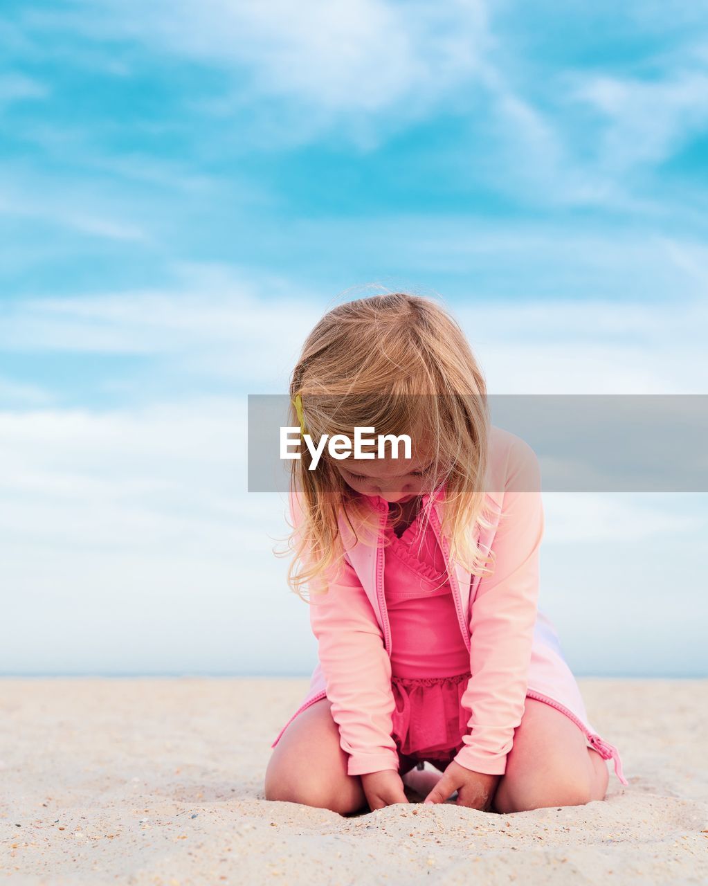 Cute girl sitting on sand at beach