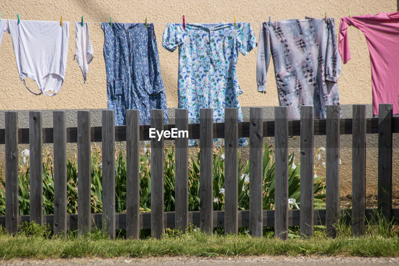 drying, hanging, laundry, clothing, clothesline, no people, textile, day, in a row, side by side, nature, home fencing, fence, architecture, grass, outdoors, clothespin, plant, built structure, building exterior