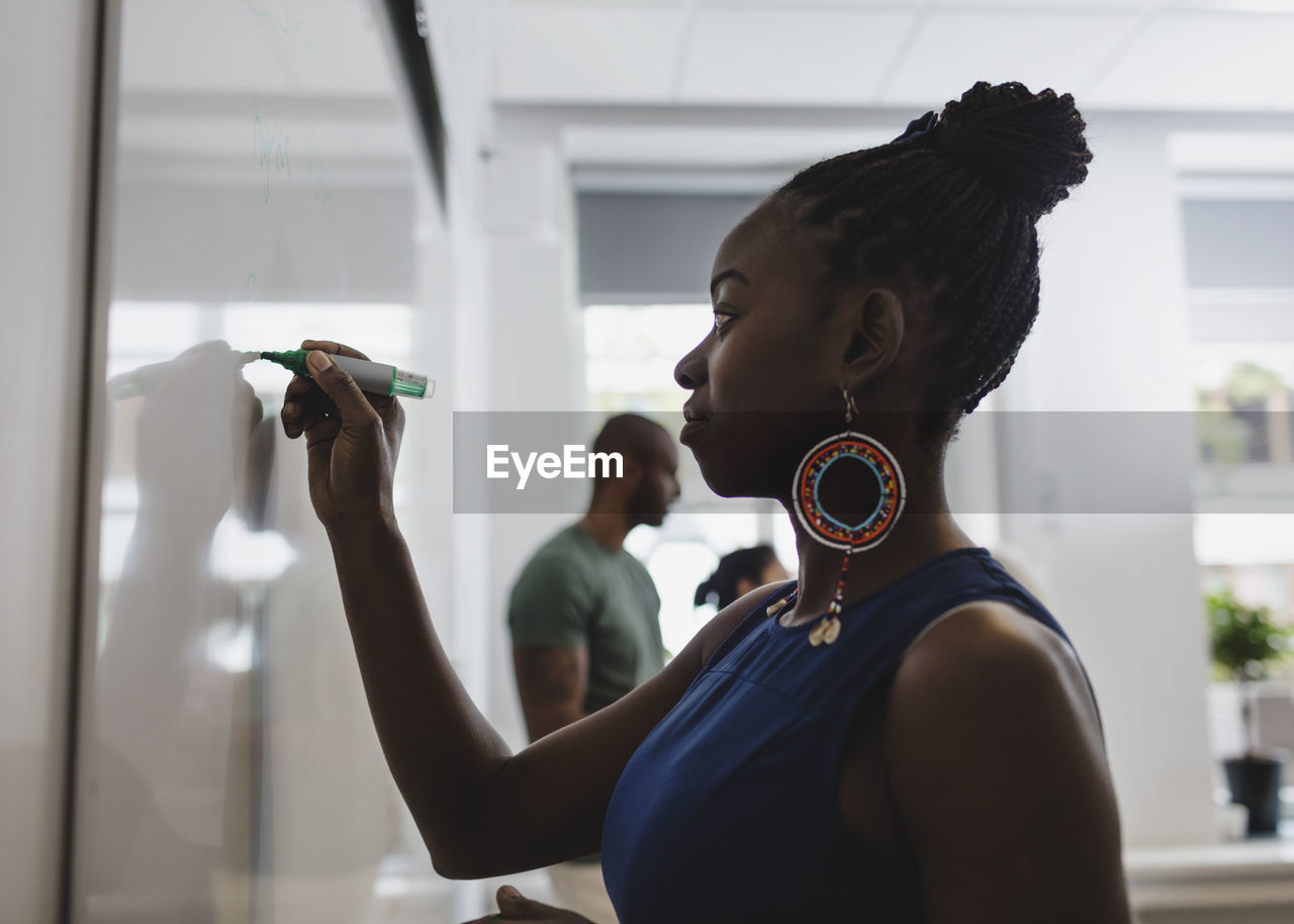 Side view of student writing on whiteboard in language class