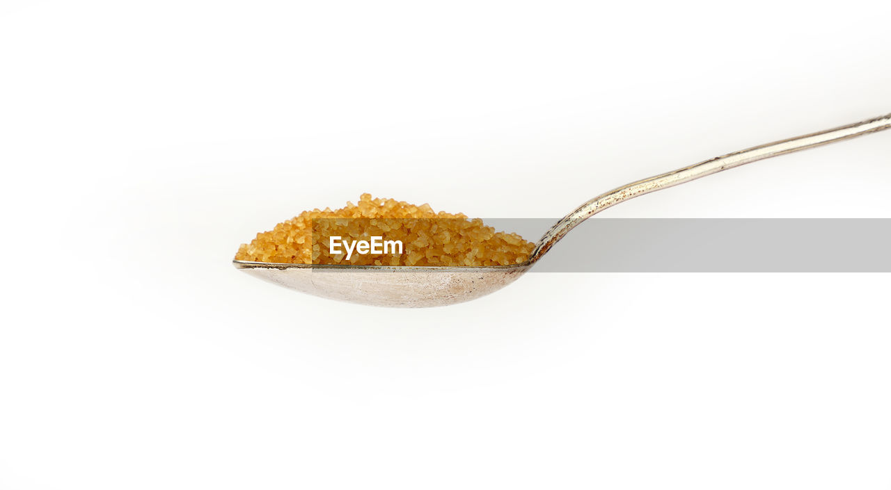 Close-up of spoon with brown sugar against white background
