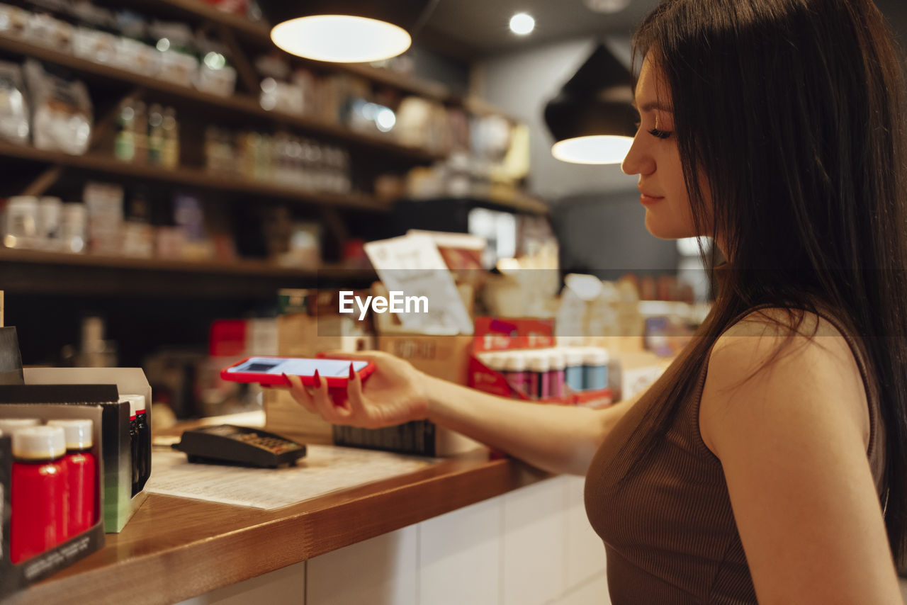 side view of young woman drinking coffee at cafe