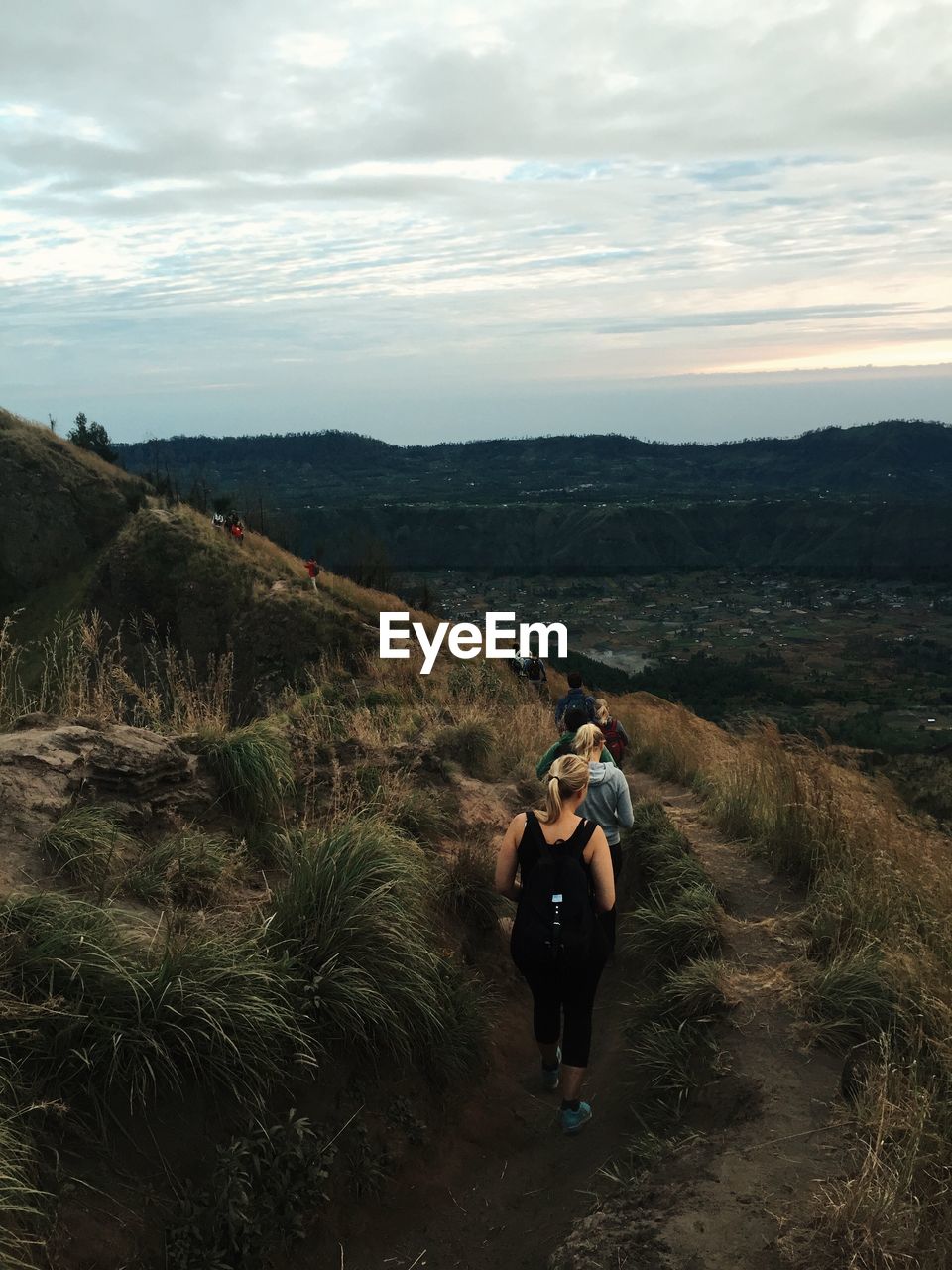 People hiking on mountain at gunung batur against cloudy sky during sunset