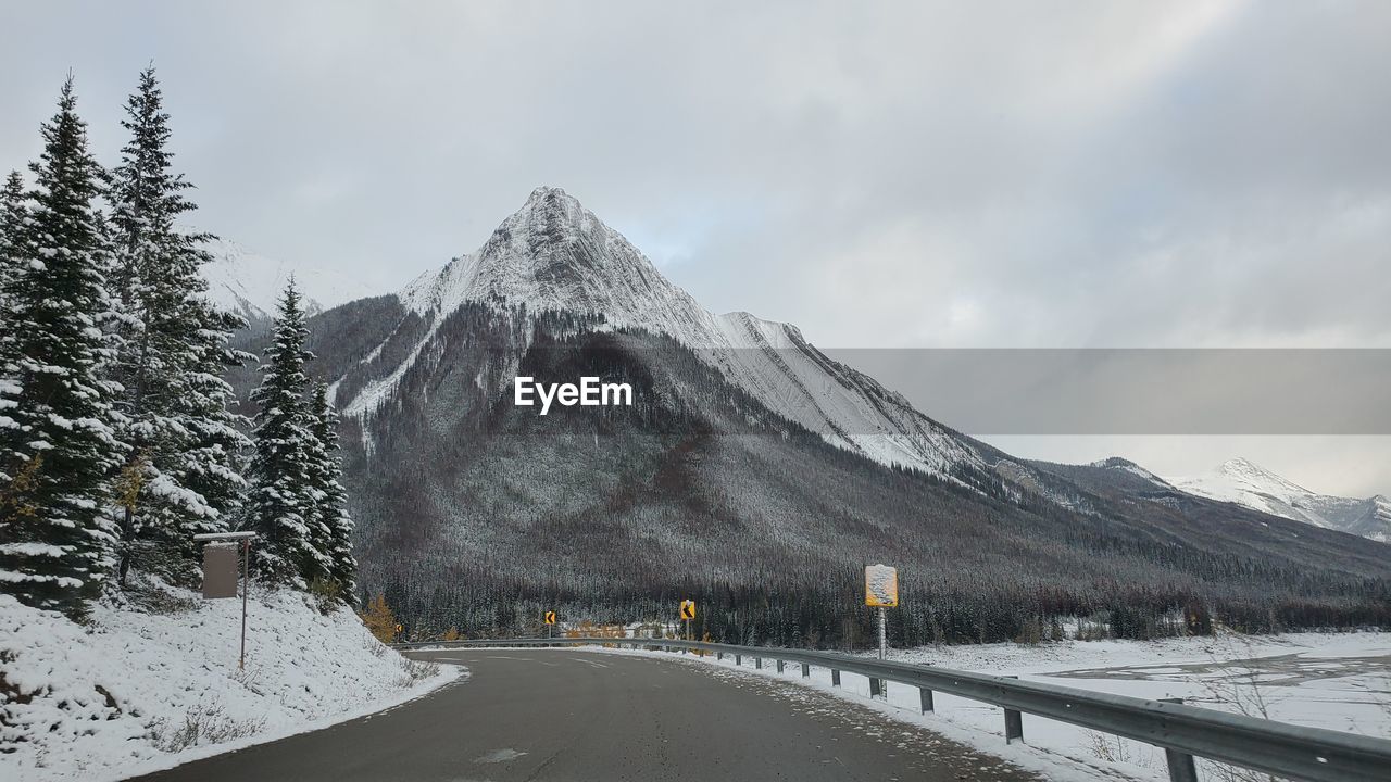 Road by snow covered mountain against sky