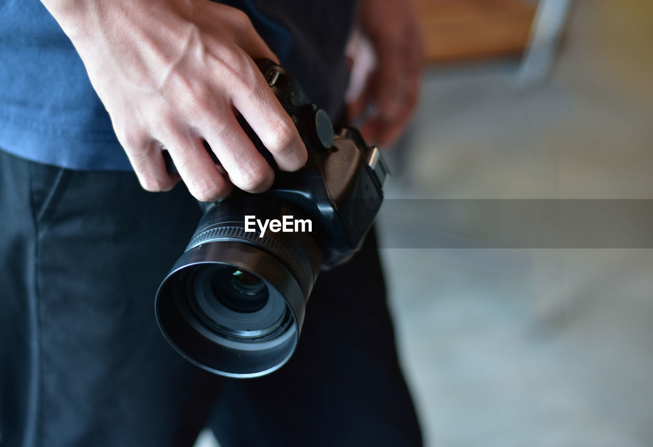 Midsection of man holding camera