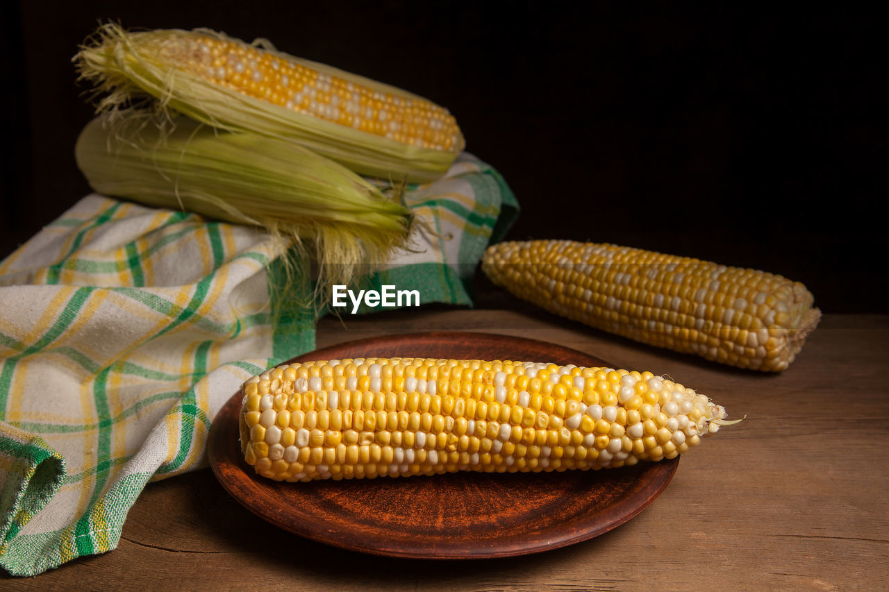 midsection of woman holding corn against black background