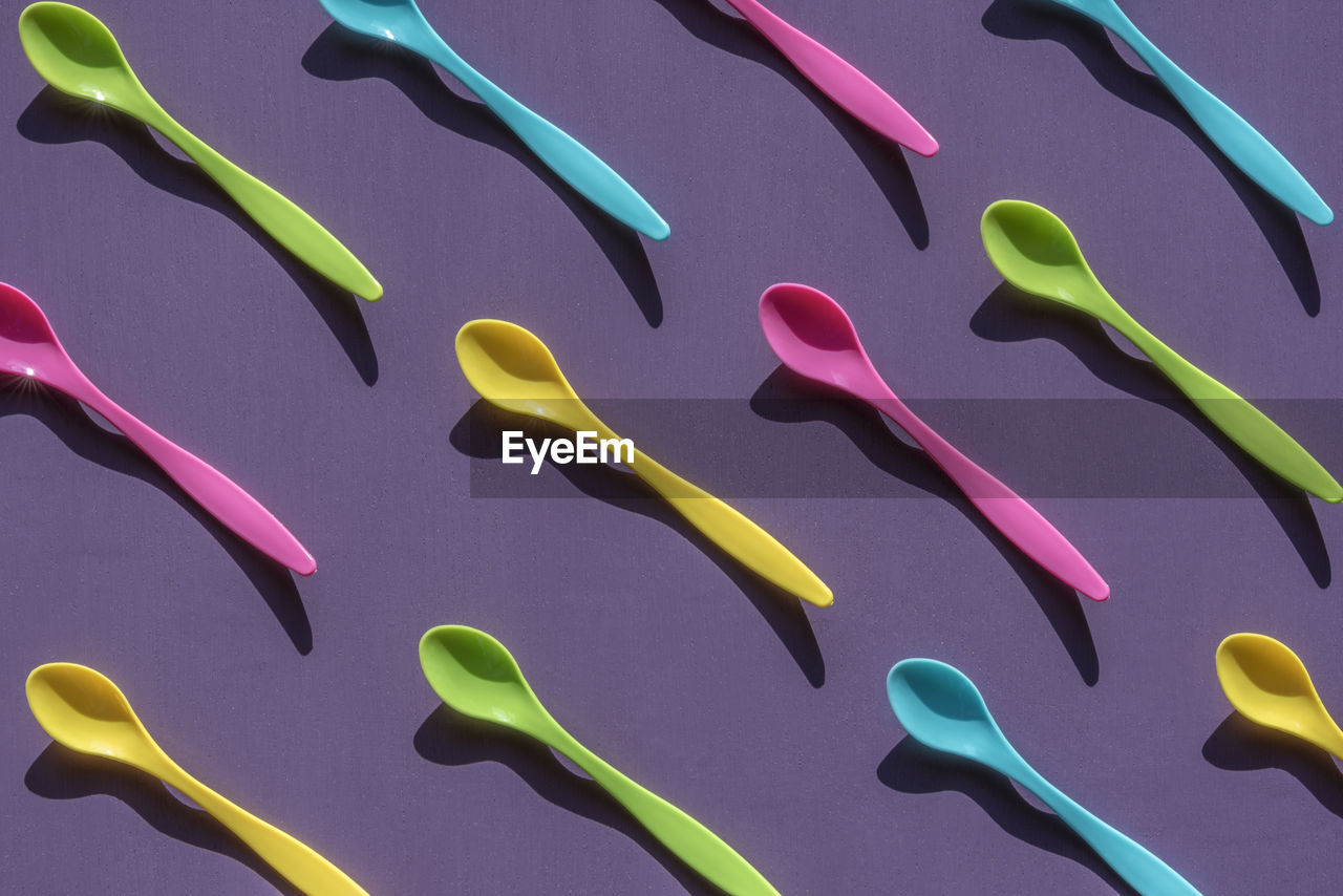 Full frame shot of multi colored spoons on purple table