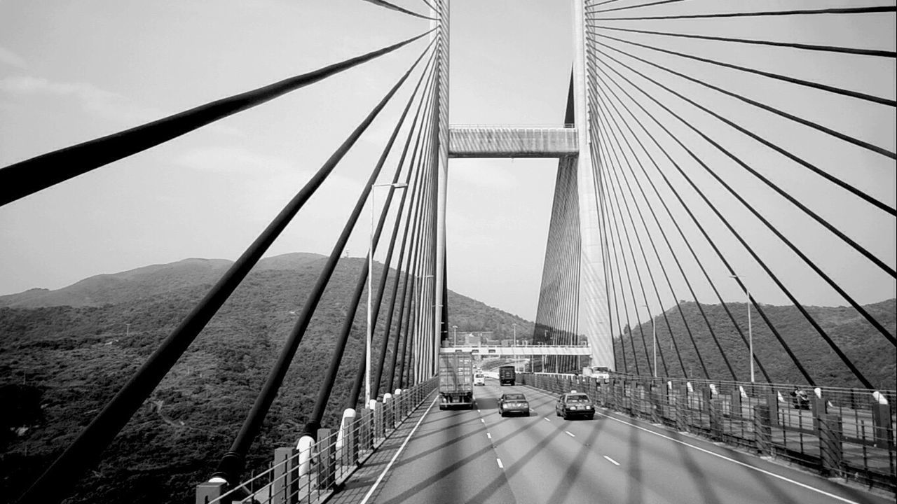 Cars moving on bridge over mountains against clear sky
