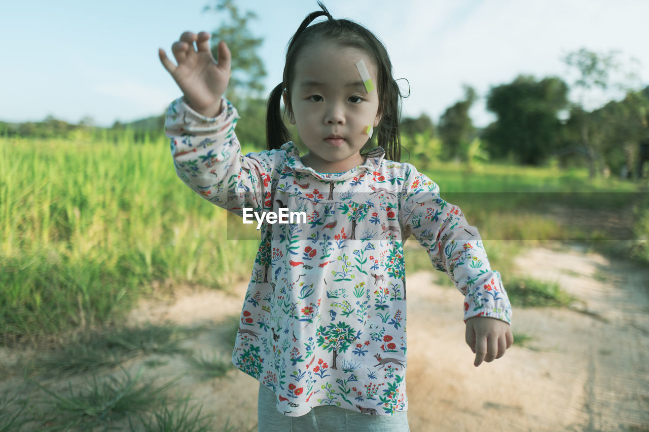 Portrait of cute girl with bandages on face standing on land