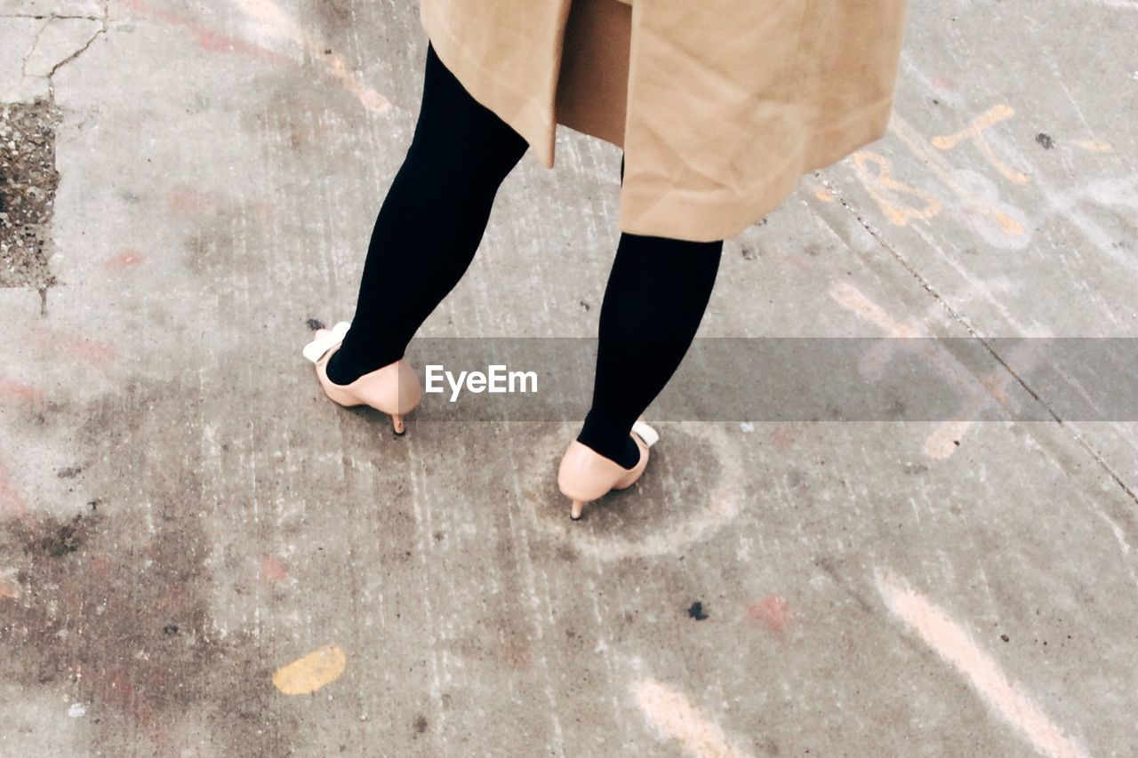 Low section of woman standing on footpath