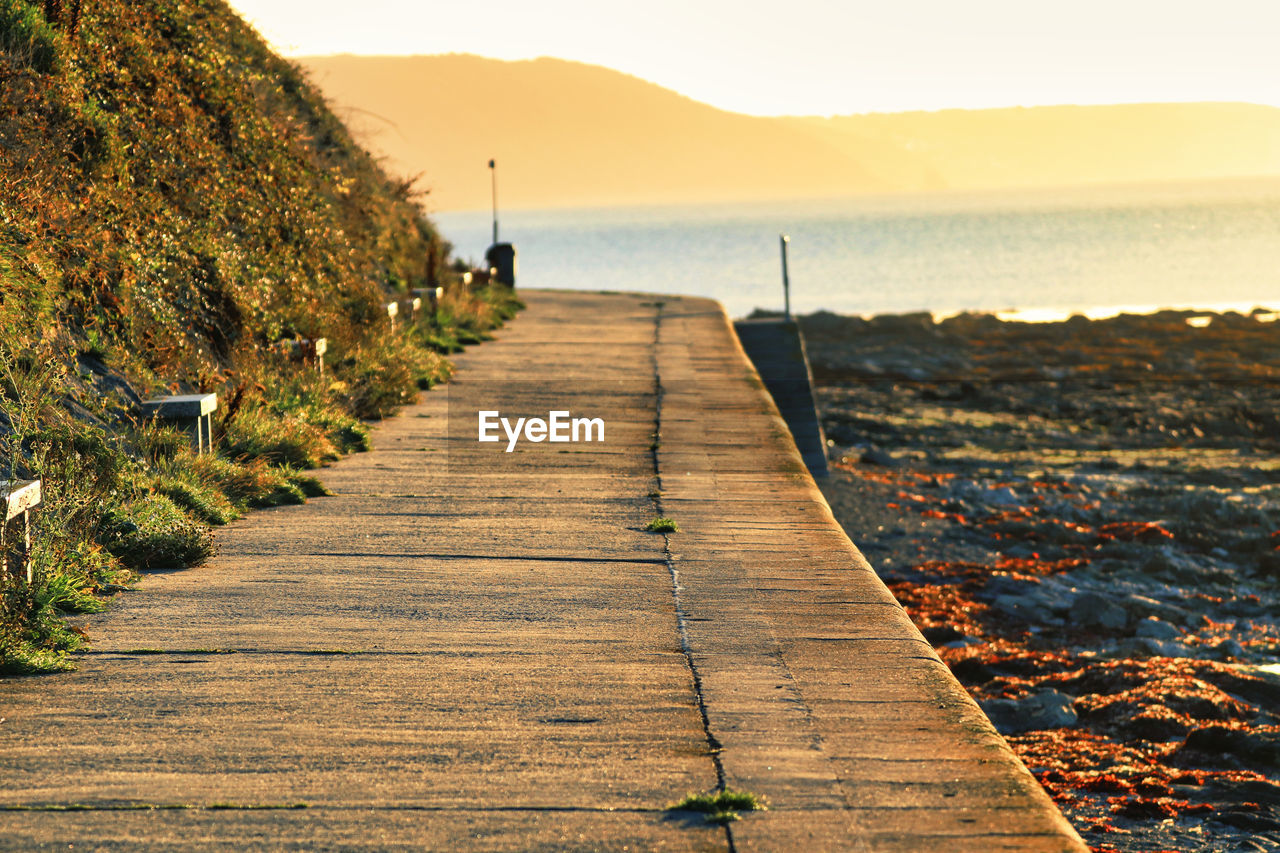 water, shore, coast, sky, nature, sea, land, beauty in nature, scenics - nature, the way forward, beach, footpath, tranquility, tranquil scene, sunlight, morning, horizon, landscape, ocean, outdoors, mountain, wood, travel destinations, body of water, environment, non-urban scene, day, idyllic, rock, boardwalk, plant, travel, pier, architecture, holiday, vacation, trip, walkway, no people, diminishing perspective, transportation, reflection, tree, coastline, leisure activity