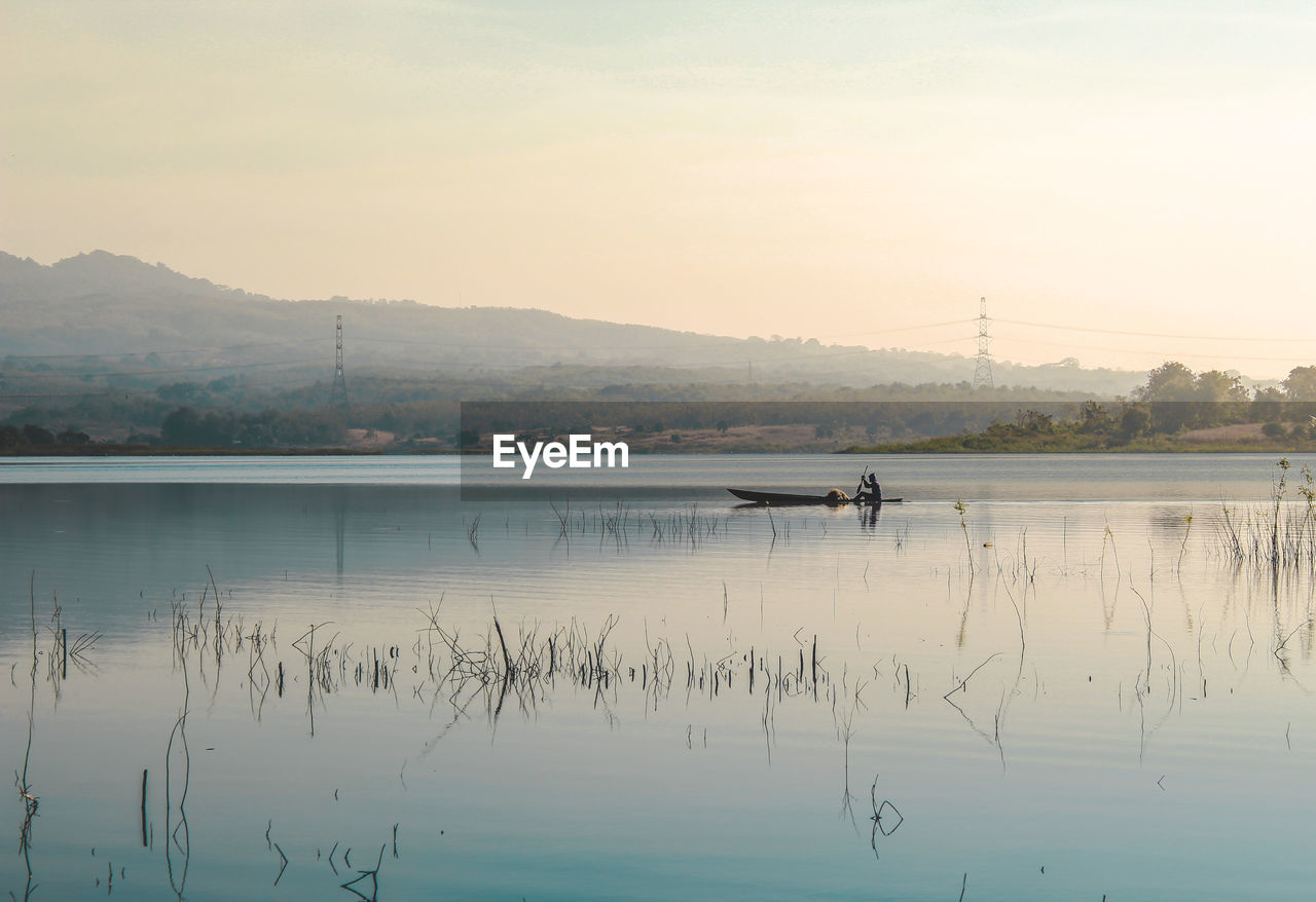 Local people sail the lake with his wooden boat in the morning atmosphere. morning view and mountain 