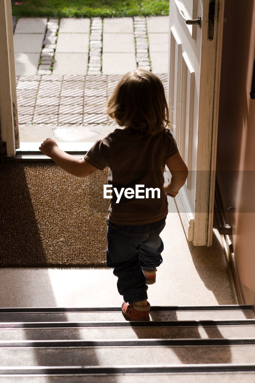 Rear view of girl walking on staircase at home