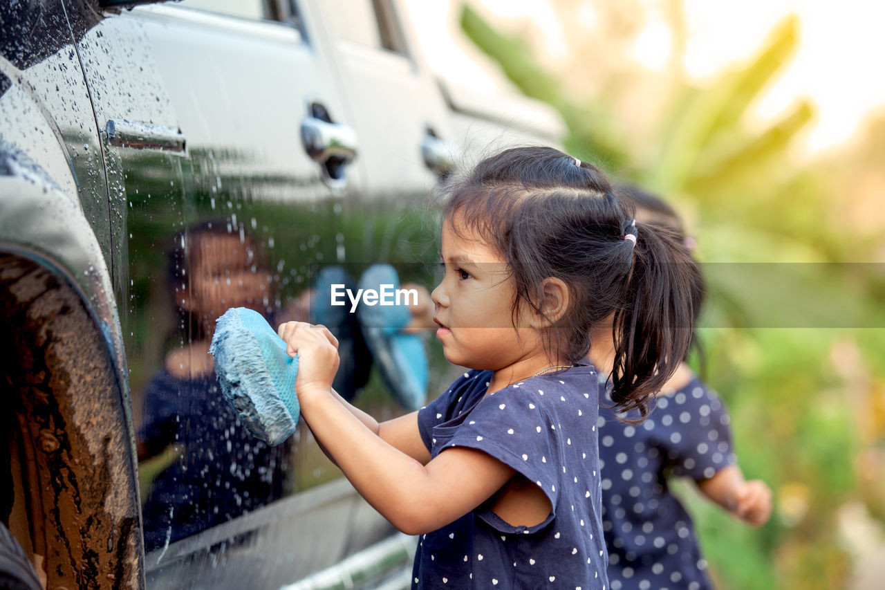 Side view of girl cleaning car