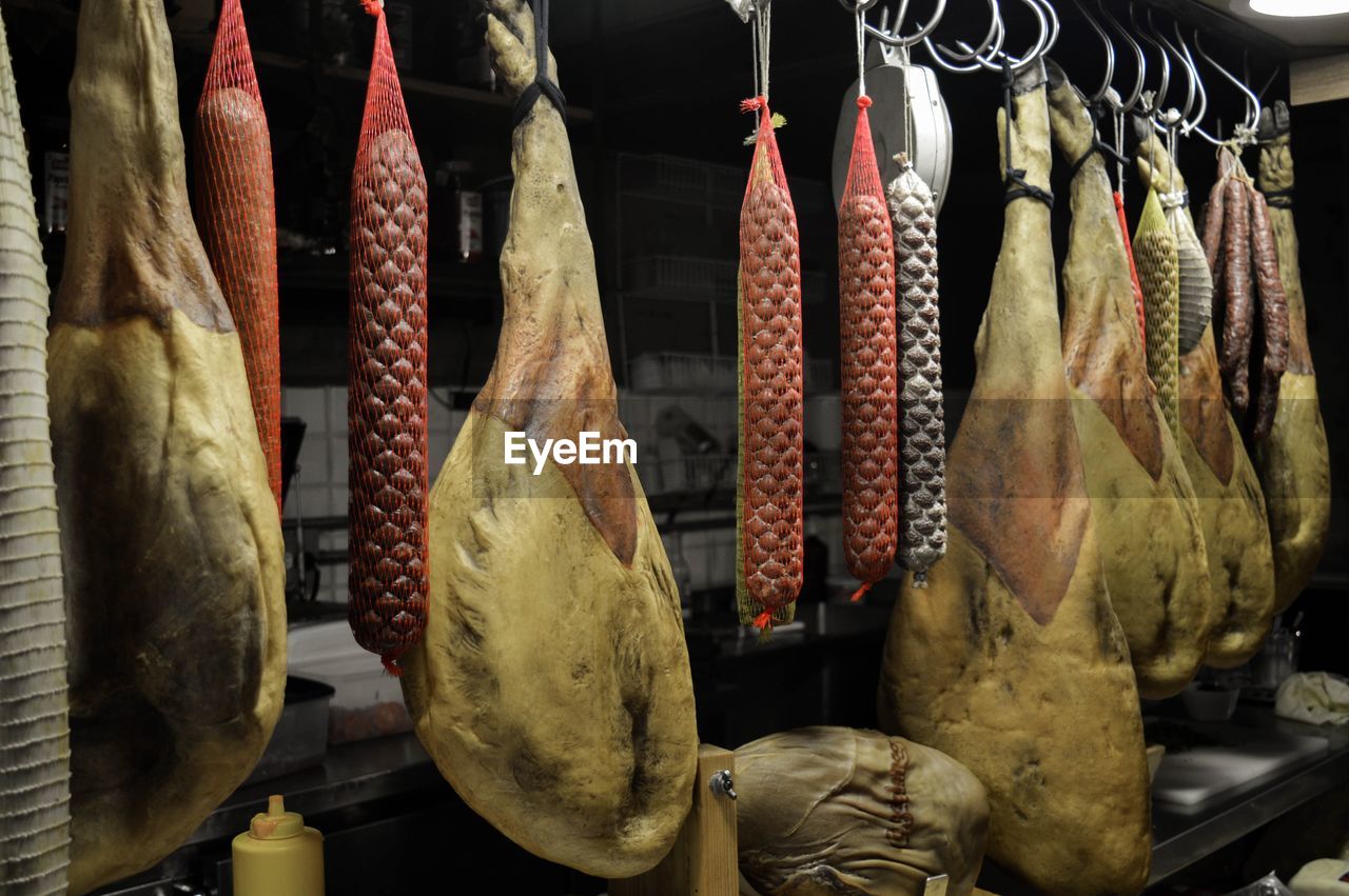 Prosciutto hams hanging in butcher shop