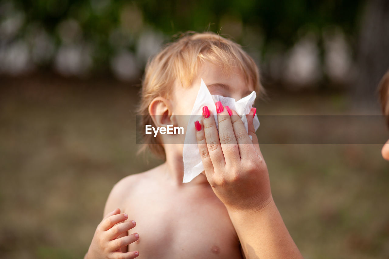 Cropped hand of mother wiping mouth of son 