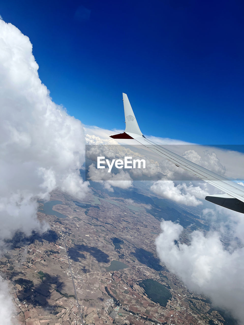 cropped image of airplane wing against clouds