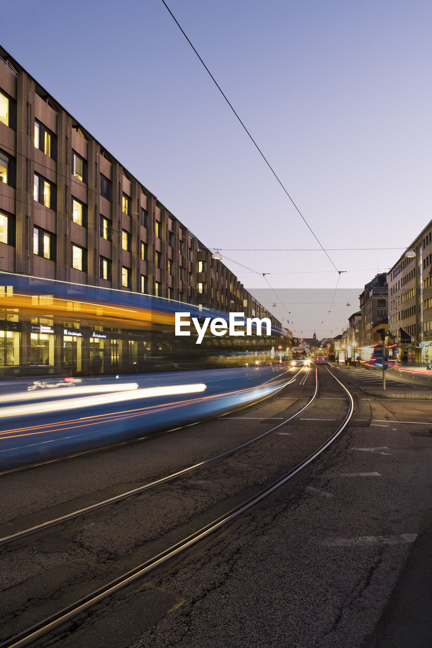 Moving tram on street in city at dusk