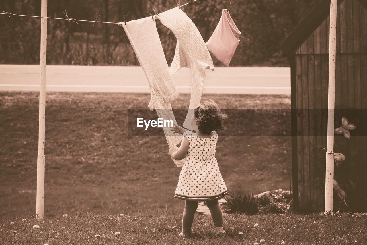 Girl holding fabric hanging on clothesline in yard