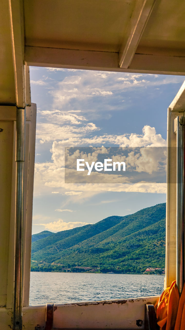 Sea and mountain against sky seen through window