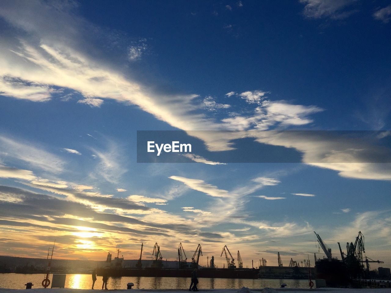 Silhouette of harbor against sky during sunset