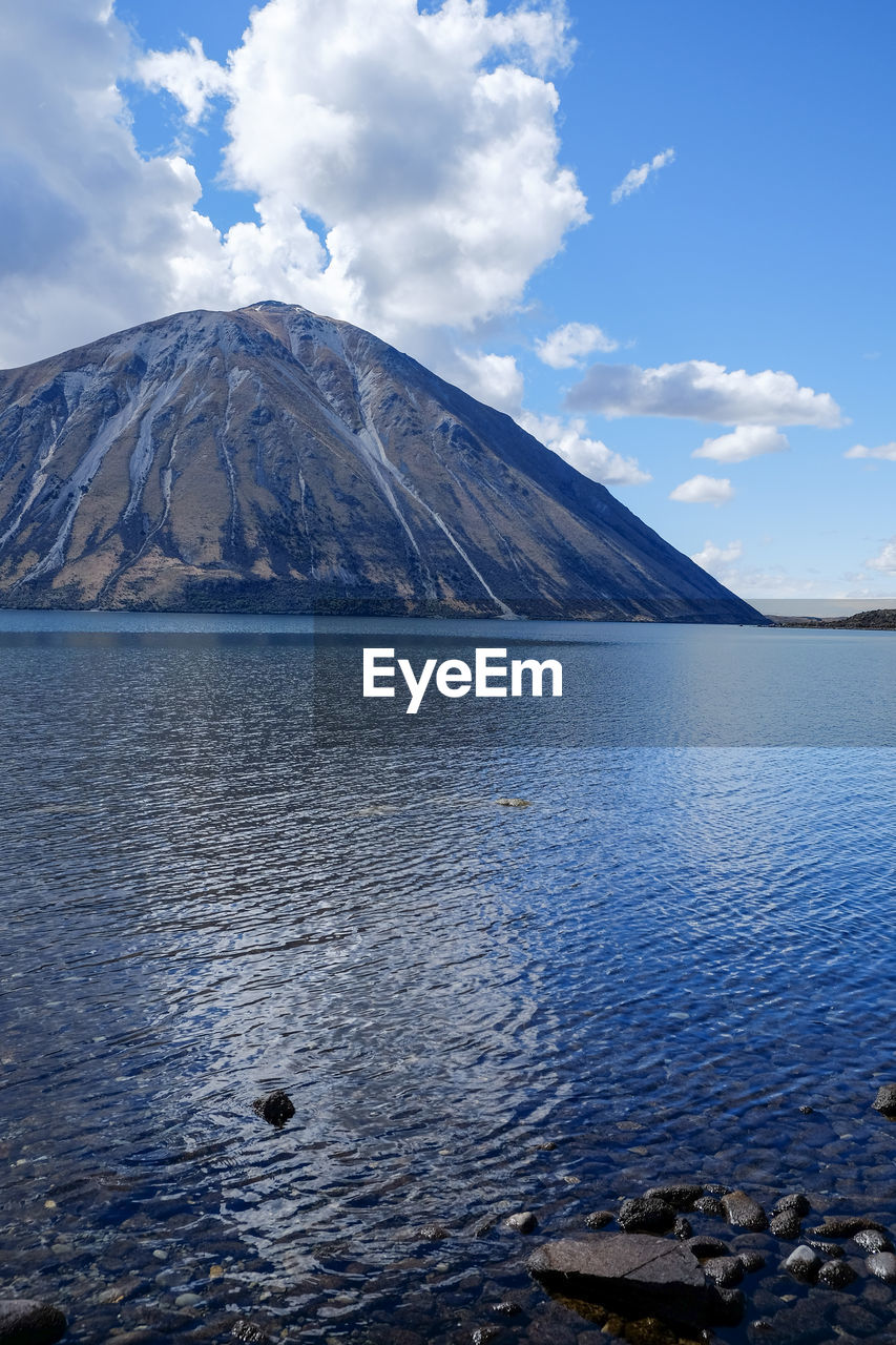 Scenic view of lake by mountain against sky