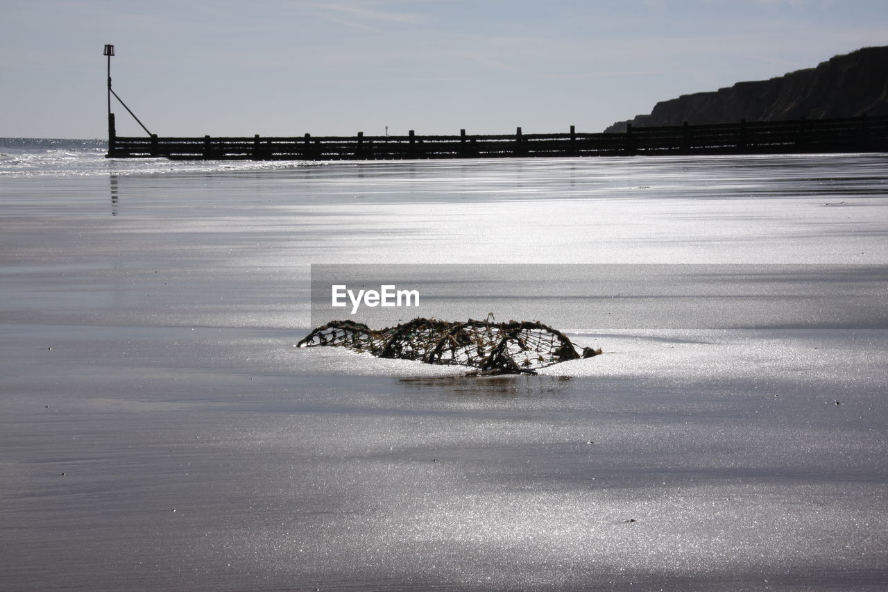 Crab pot at beach against sky