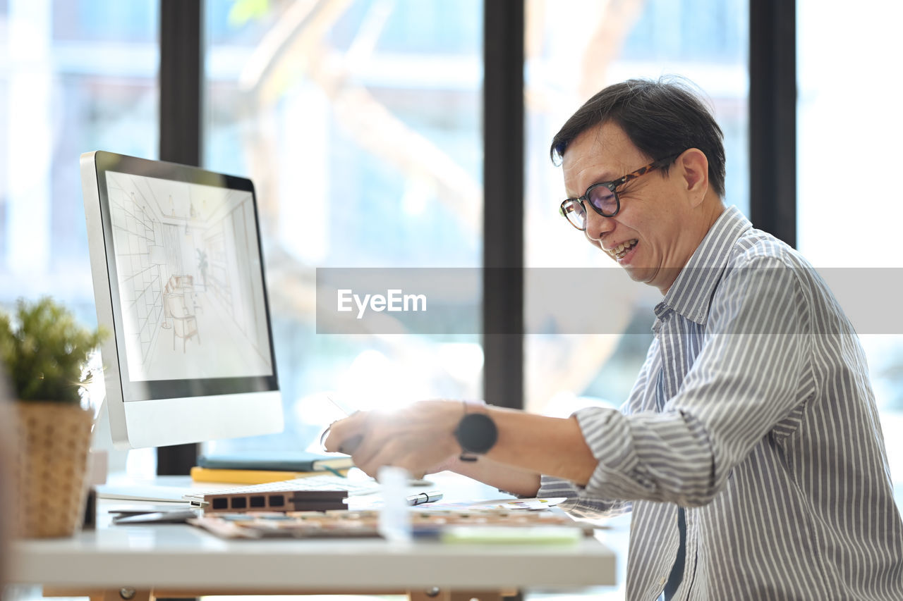 side view of businessman using laptop while sitting at office