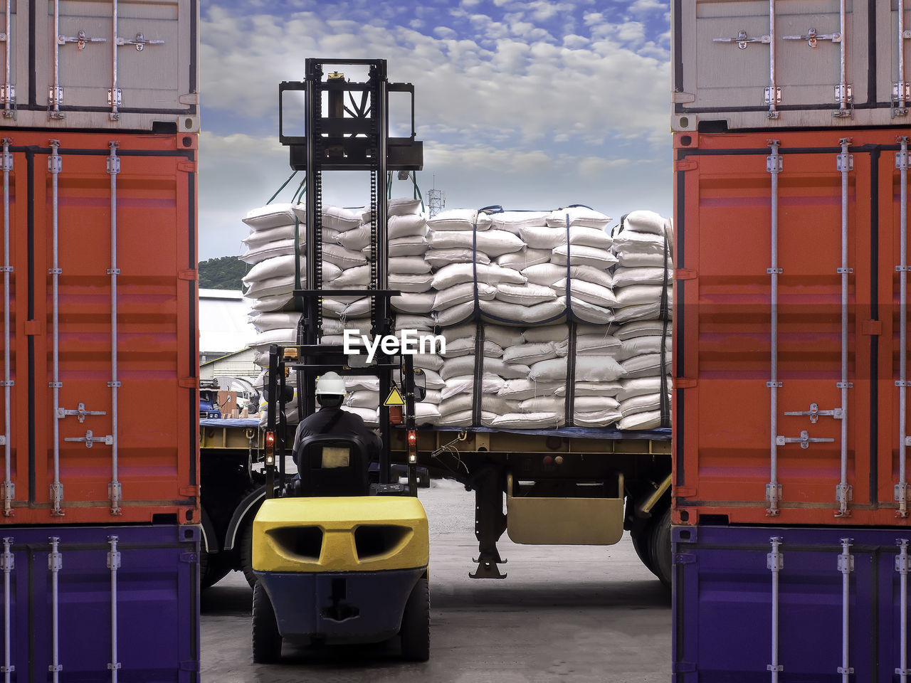 Rear view of man operating fork lift against sky
