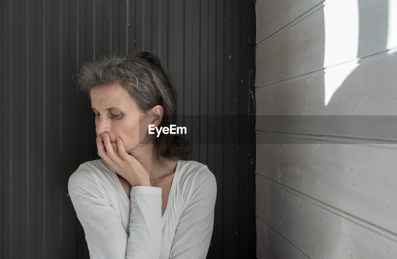 Thought woman standing by wall