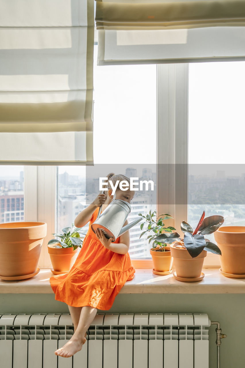 Woman standing by potted plant on table