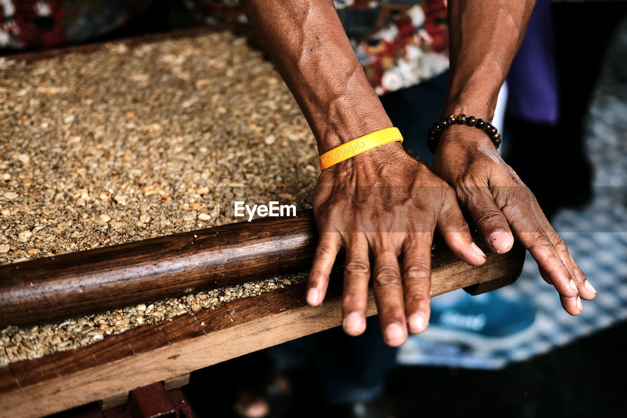 Cropped hands of man preparing peanut brittle with rolling pin