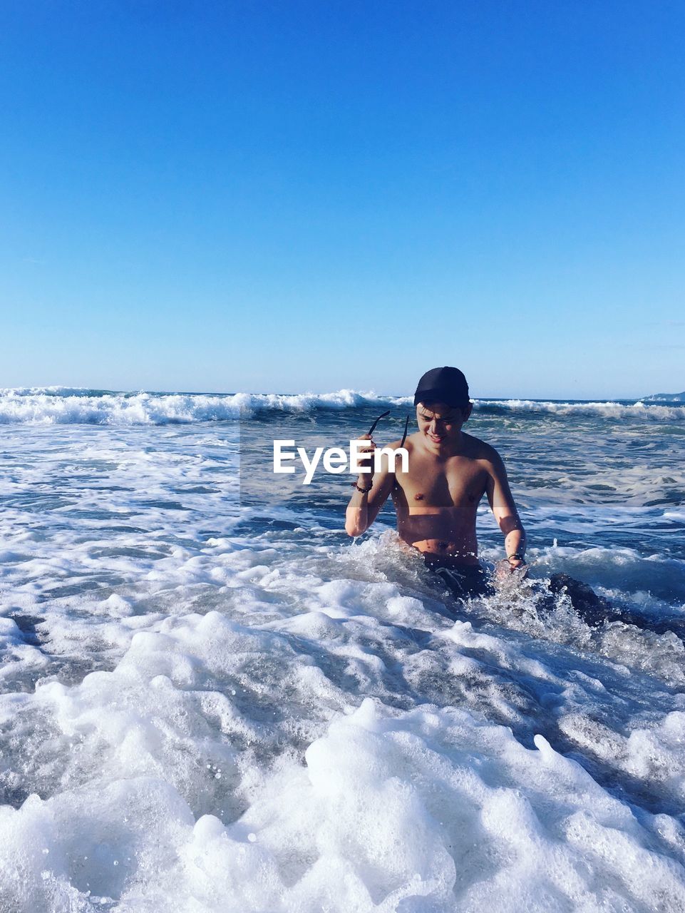 Shirtless man in sea against clear sky