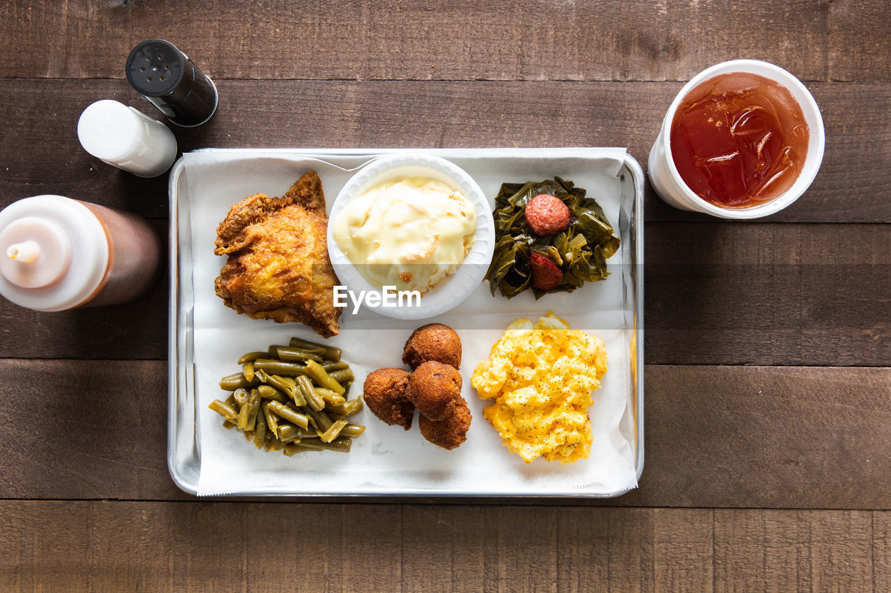 A tray of fried chicken, green beans, mac & cheese meal with sweet tea