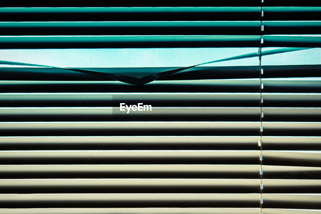 Full frame of horizontal window blinds in gradient blue green cream color a single panel creased