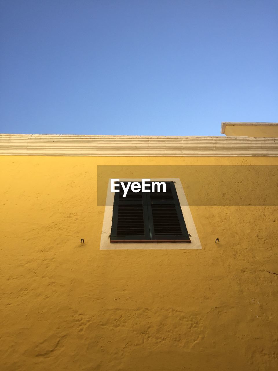 LOW ANGLE VIEW OF BUILDING AGAINST CLEAR BLUE SKY