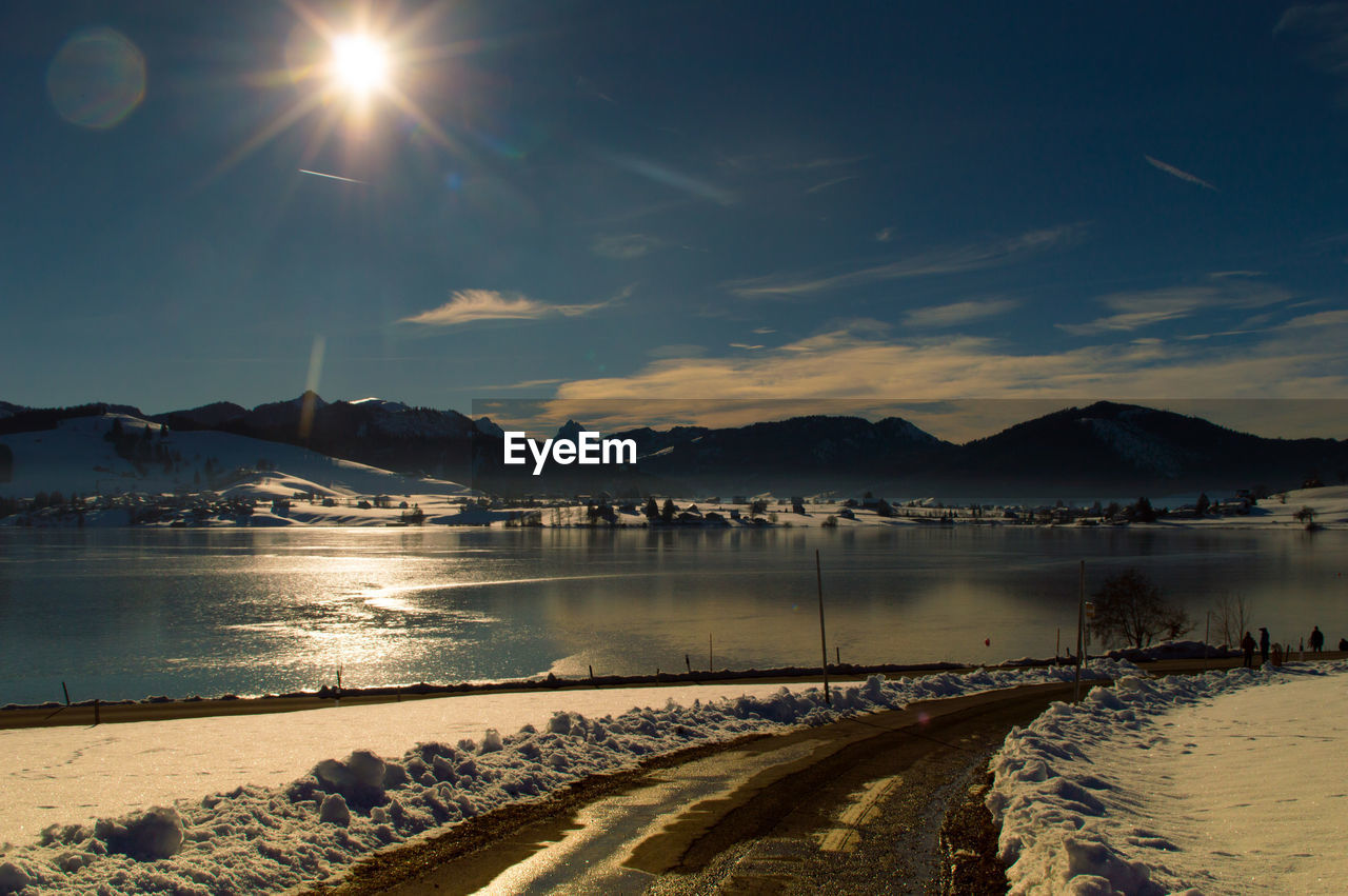 Scenic view of lake by snowcapped mountains against sky