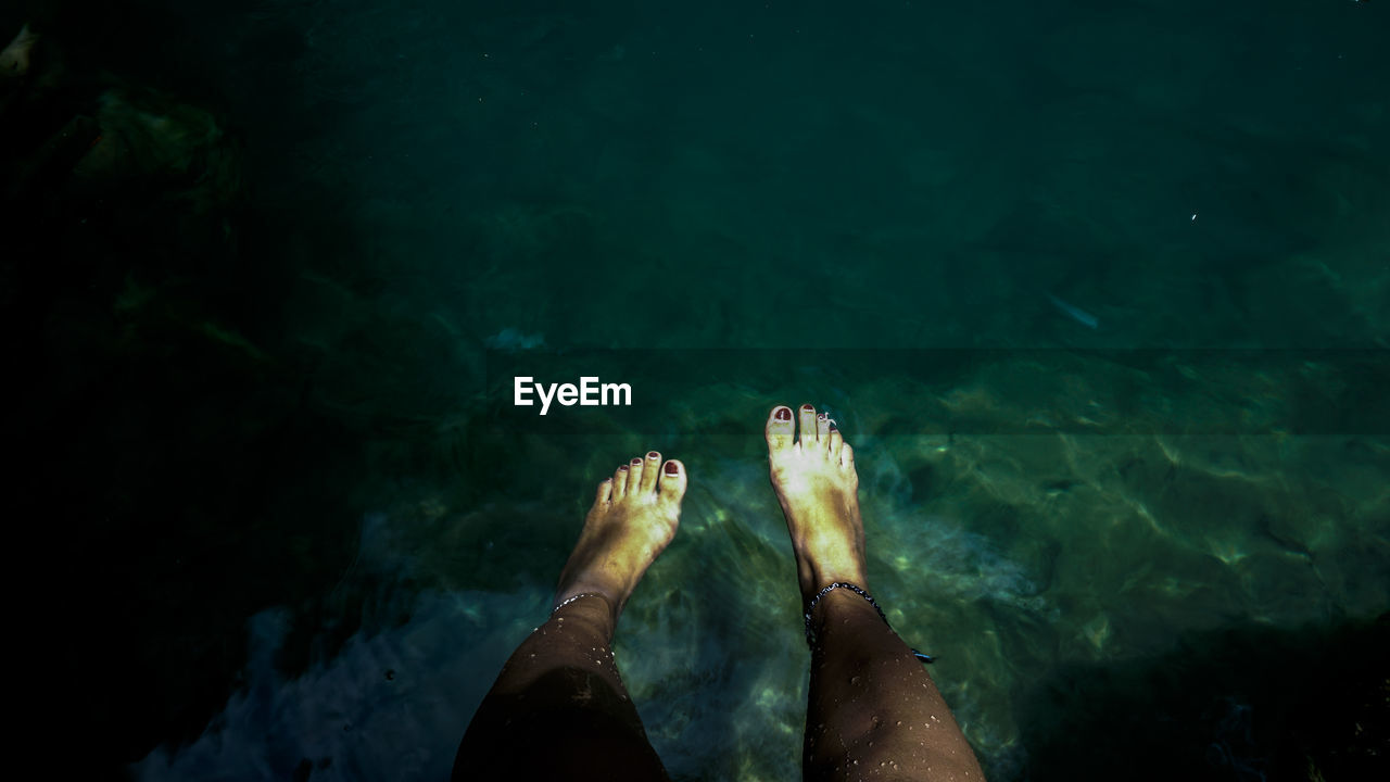 Low section of woman in sea at night