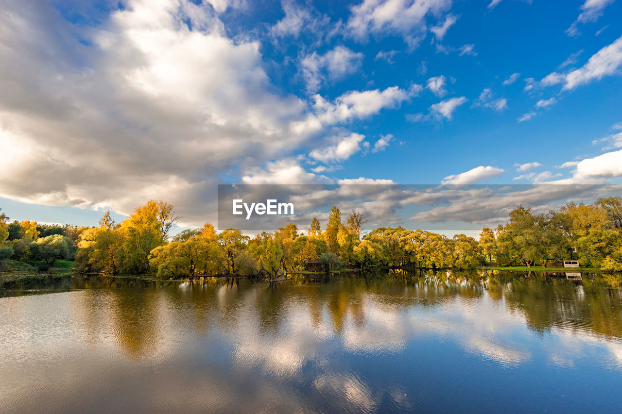 REFLECTION OF TREES IN LAKE AGAINST SKY