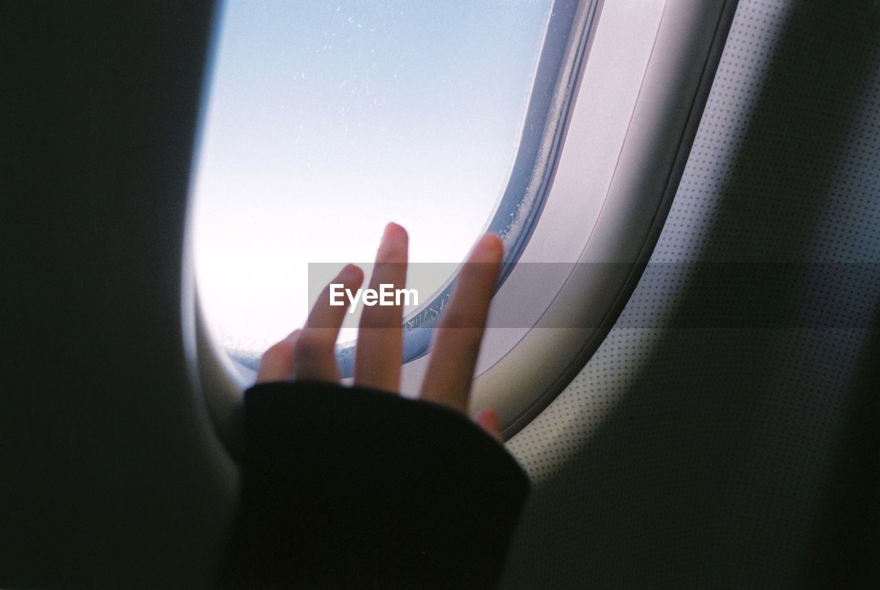 Cropped image of hand by airplane window 