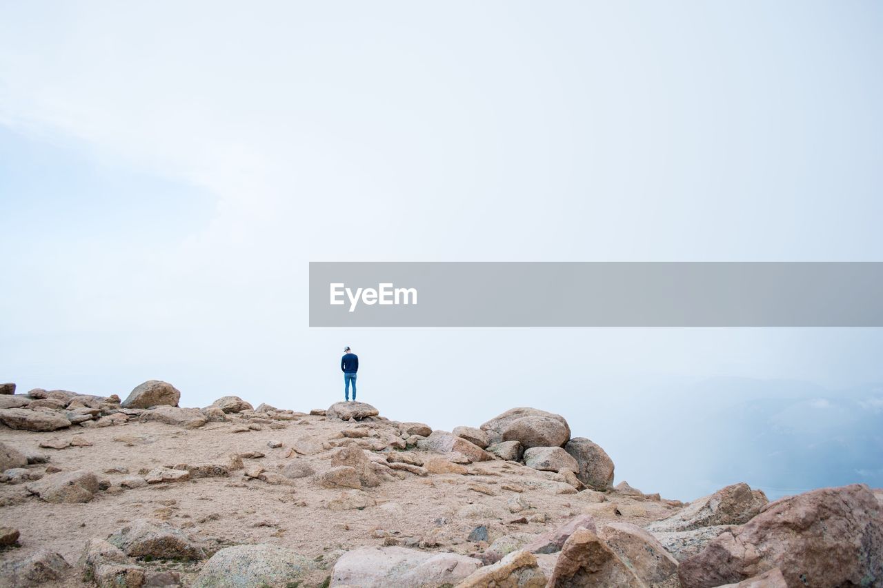 Rear view of man standing on mountain during foggy weather