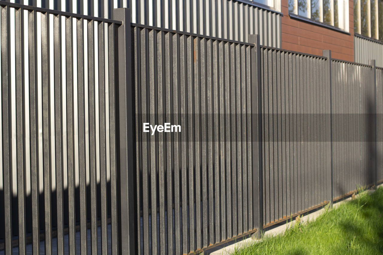 METAL FENCE BY WALL IN PARK