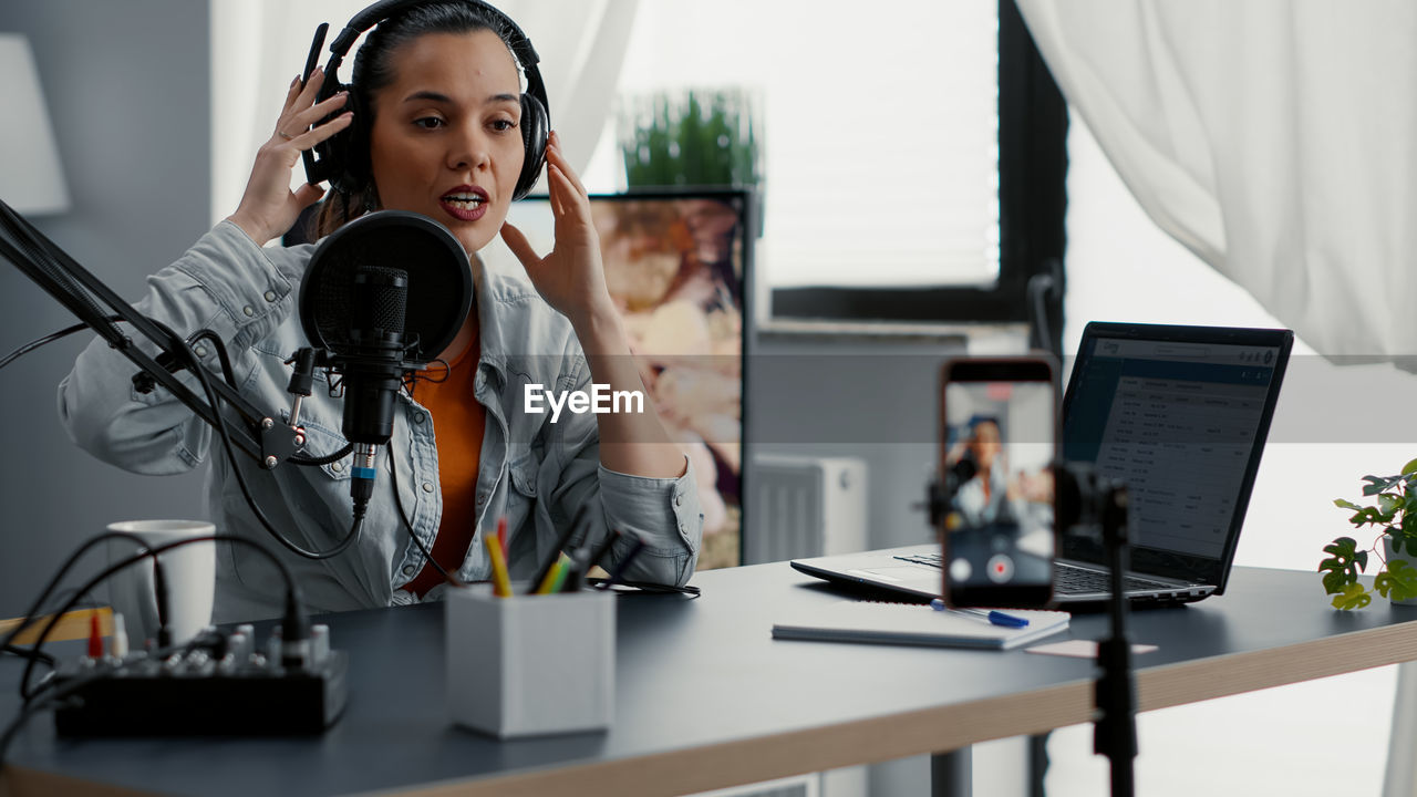 portrait of young woman using mobile phone while sitting in office