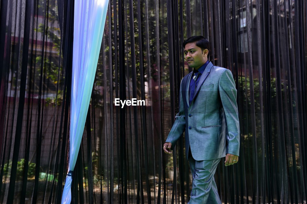 Young man walking by curtains