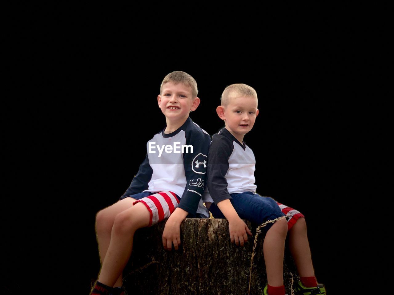 FULL LENGTH PORTRAIT OF BOYS SITTING AGAINST BLACK BACKGROUND