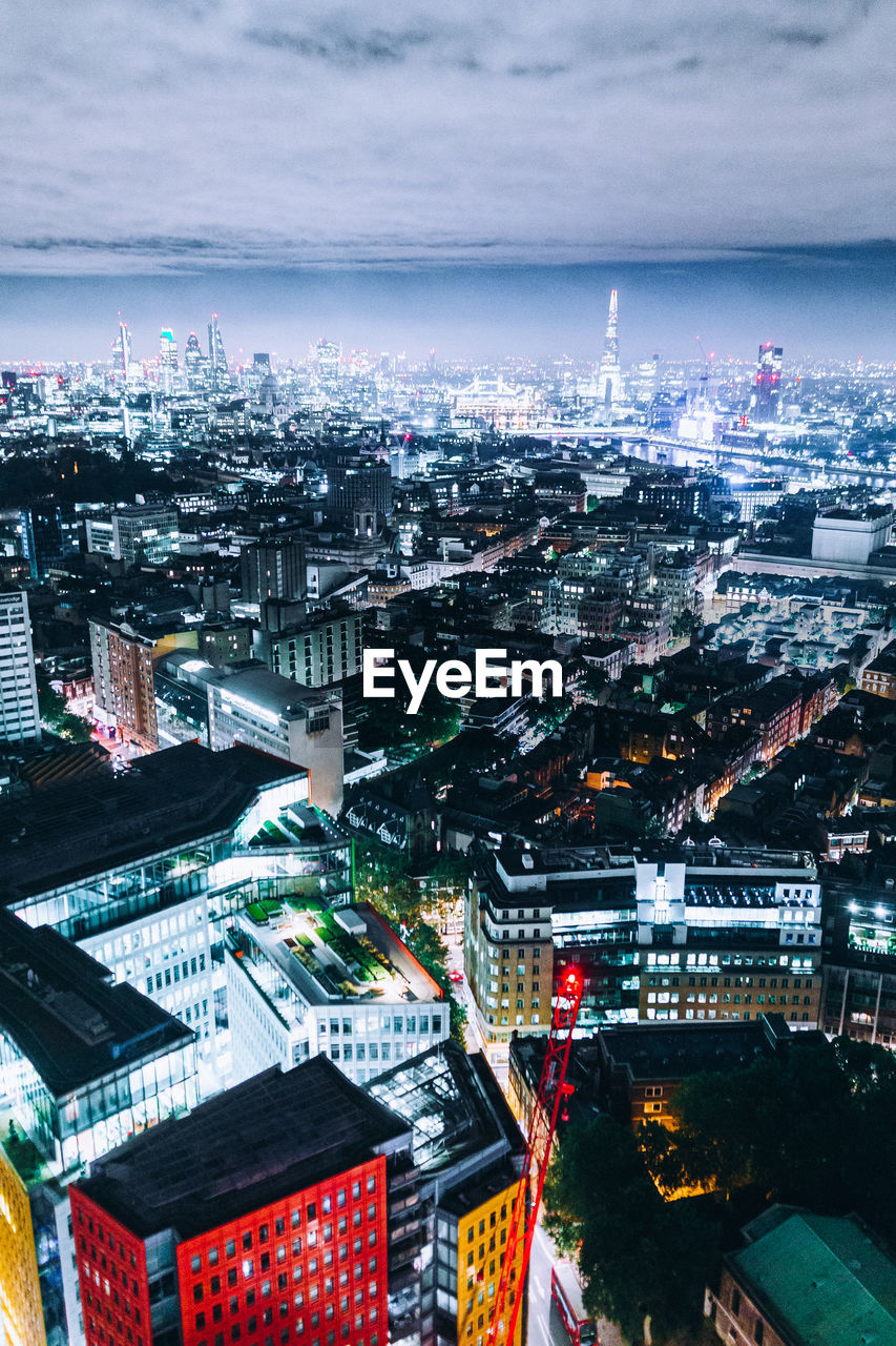 Aerial view of illuminated cityscape against cloudy sky at dusk