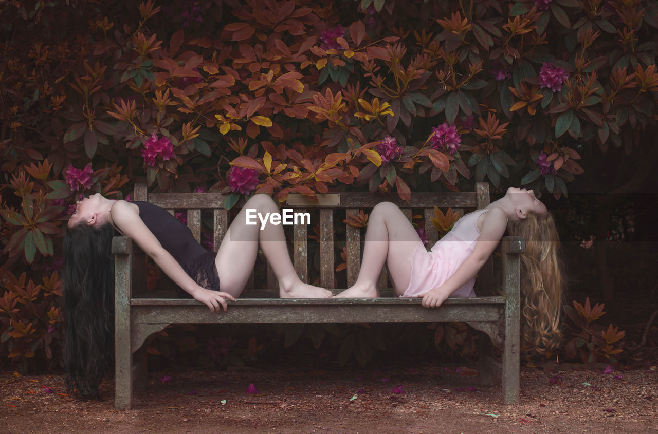 WOMAN SITTING ON CHAIR AGAINST PINK FLOWERS