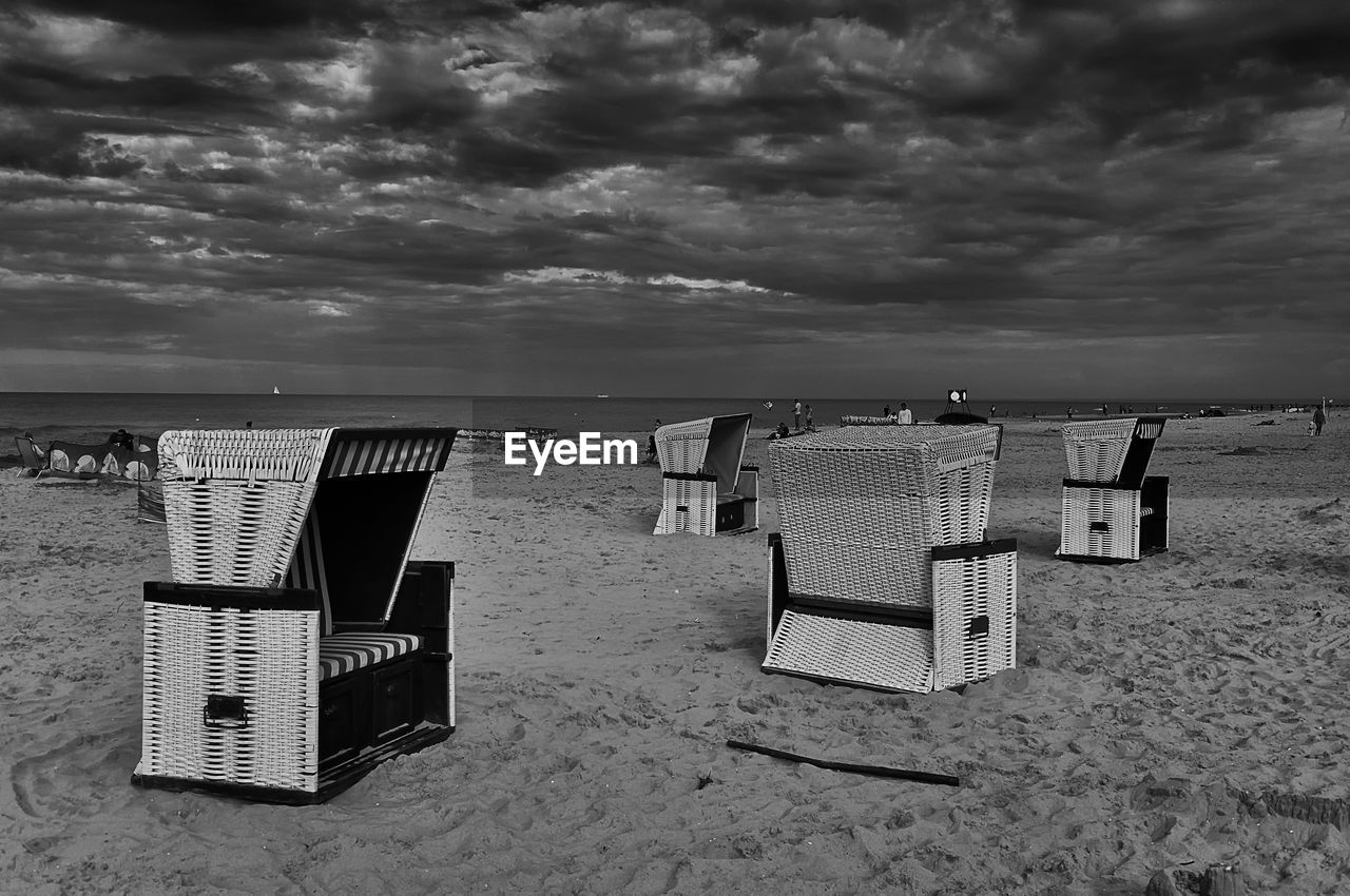 HOODED CHAIRS ON BEACH AGAINST SEA