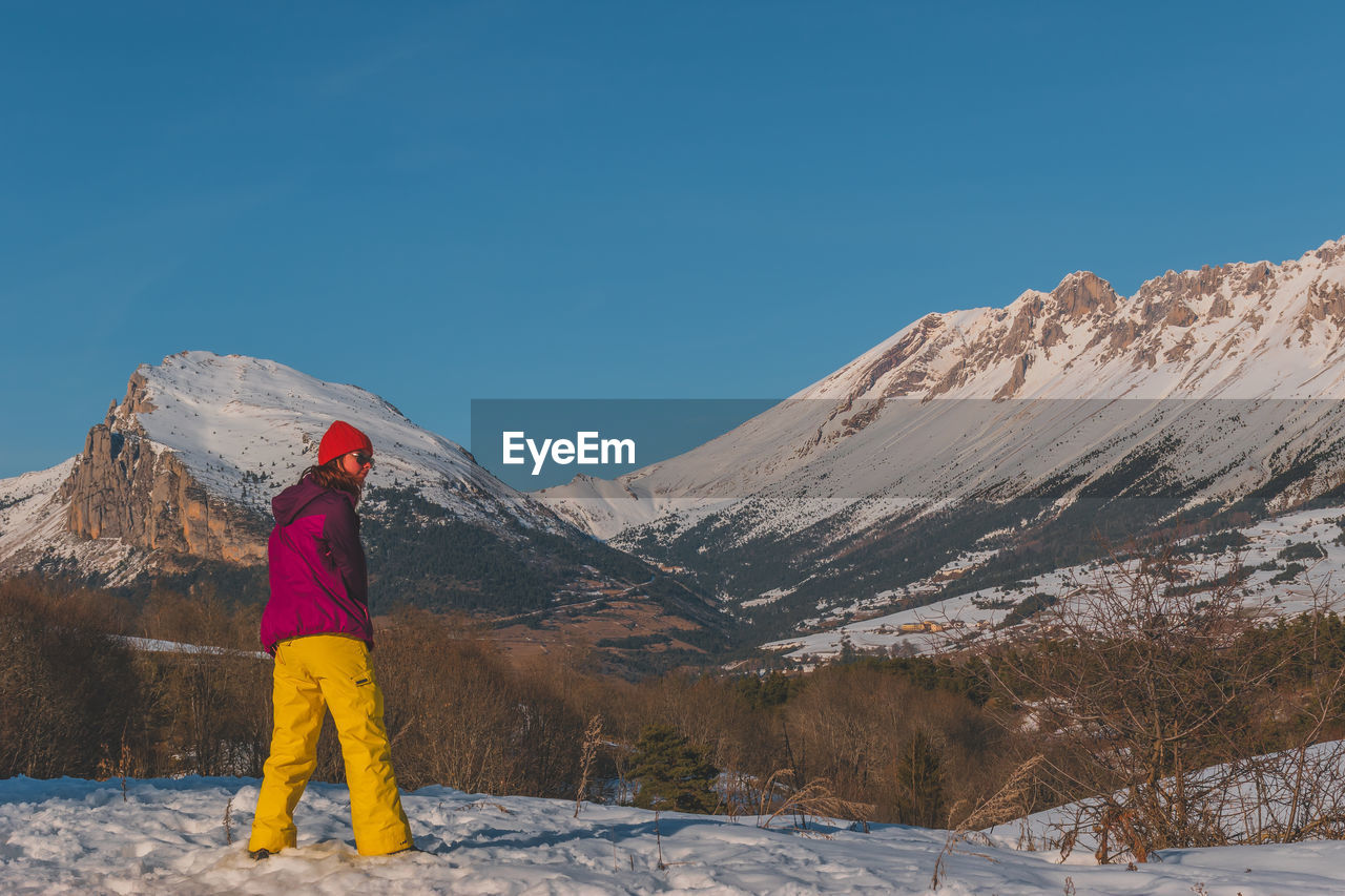 mountain, snow, winter, cold temperature, one person, mountain range, scenics - nature, environment, beauty in nature, sky, leisure activity, nature, full length, landscape, clothing, adult, adventure, travel, snowcapped mountain, sports, travel destinations, vacation, standing, activity, warm clothing, holiday, day, trip, skiing, clear sky, blue, hiking, rear view, footwear, land, tranquil scene, lifestyles, winter sports, tranquility, outdoors, ridge, young adult, copy space, non-urban scene, summit, men, solitude, mountaineering, backpack, tourism, sunny, person, exploration, remote, sunlight