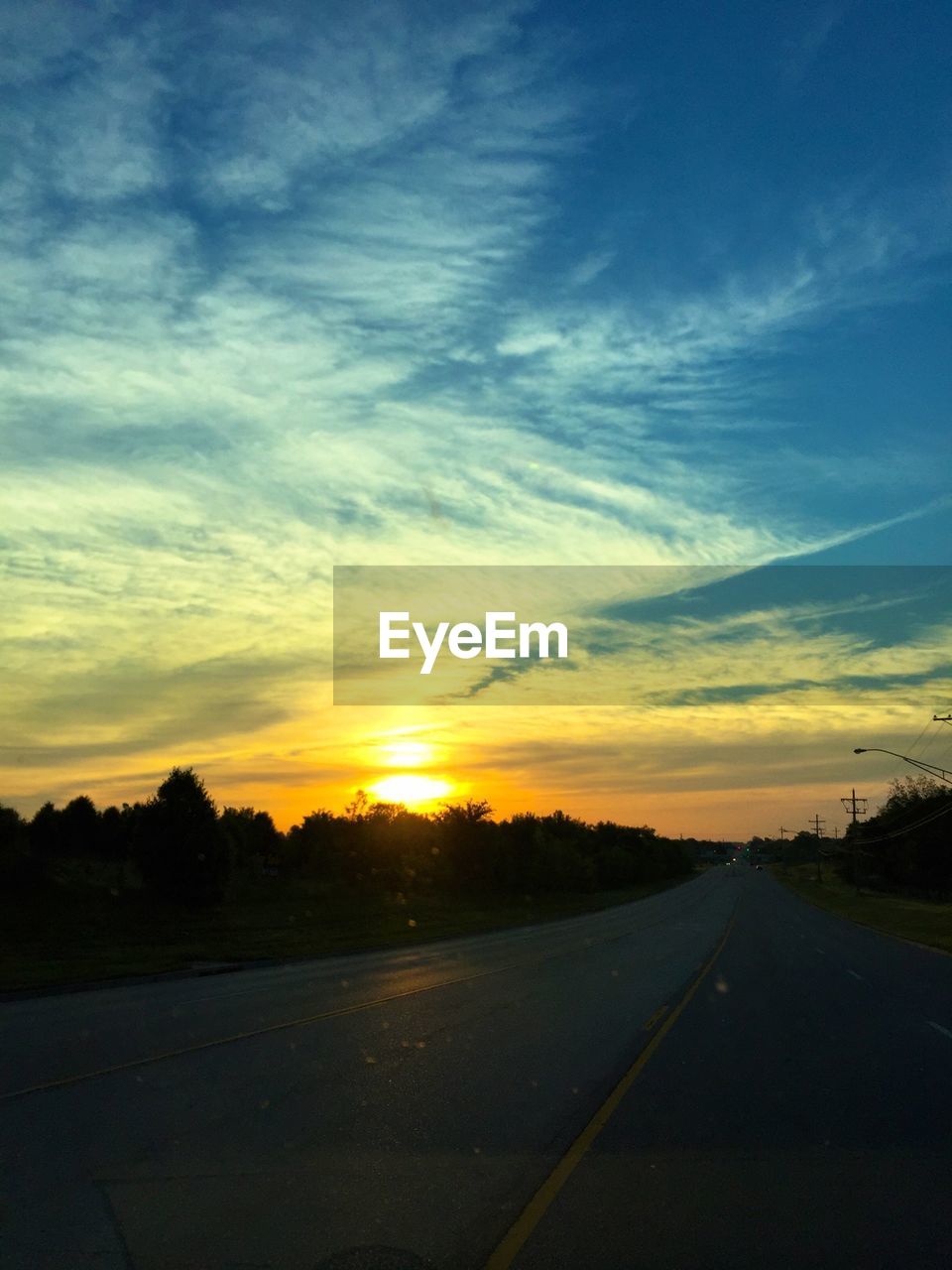 SCENIC VIEW OF COUNTRY ROAD AT SUNSET