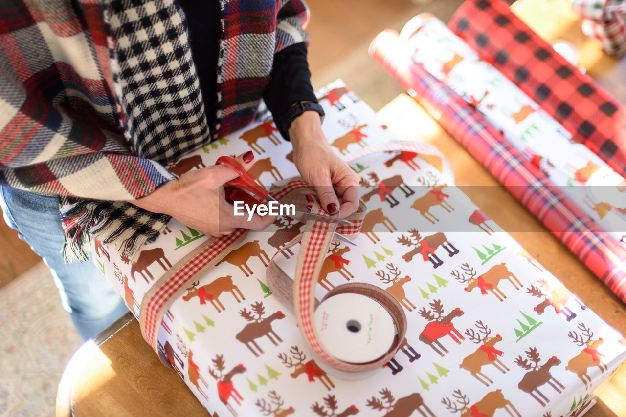 Midsection of woman wrapping gift at home